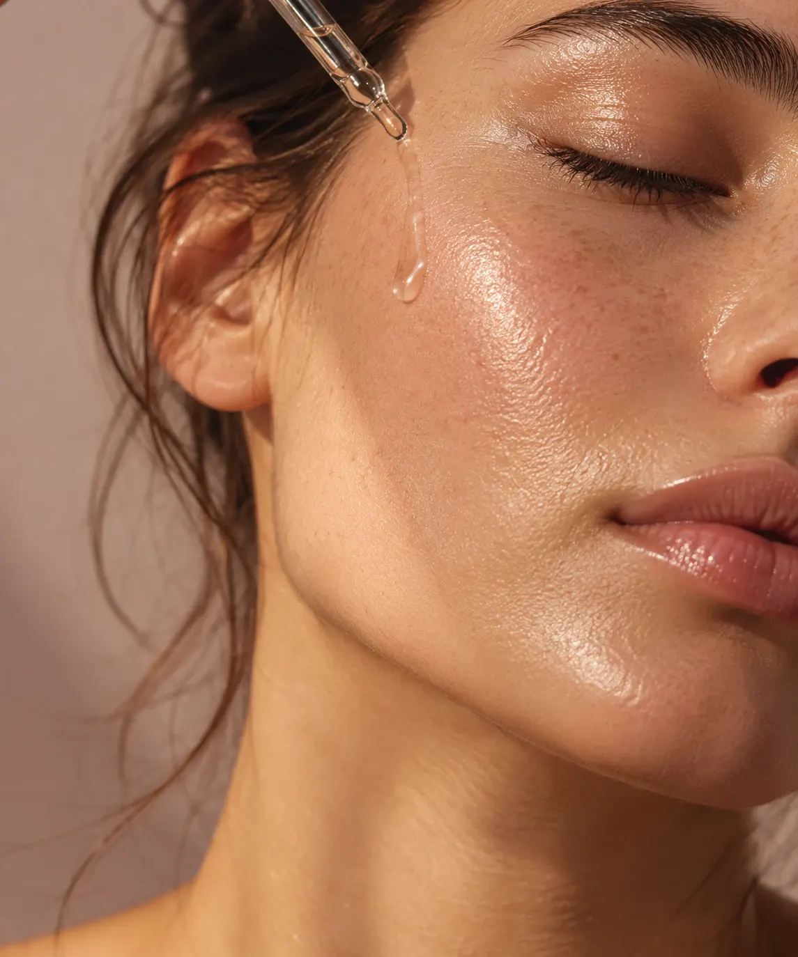 Serum dropper over dewy, glowing skin